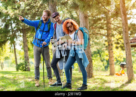 Fille randonneur avec des fellows regarder la carte en forêt Banque D'Images