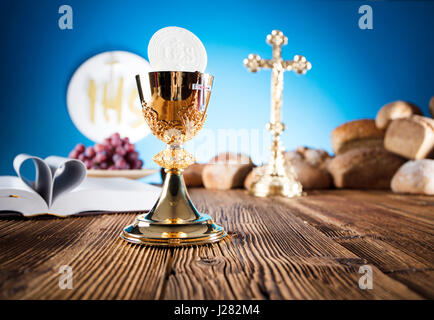 La première Communion. Thème de la religion catholique. Crucifix, Bible, du pain sur la table en bois rustique et fond bleu. Banque D'Images