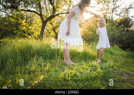 Mère enceinte danse avec sa fille on grassy field in park Banque D'Images