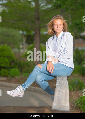 Young woman sitting on wooden fence Banque D'Images
