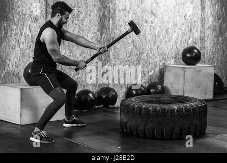 Remise en Forme Sport homme frapper avec un marteau pneumatique de roue d'entraînement Crossfit traîneau, les jeunes de l'intérieur de sport Guy sain Banque D'Images