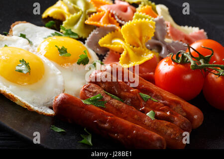 Délicieux petit déjeuner : oeufs frits, saucisses, tomates et pâtes farfalle close-up. L'horizontale Banque D'Images