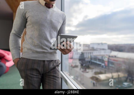 Hispanic Business Man Using Tablet Computer se placer devant la fenêtre panoramique en homme d'intérieur Bureau Coworking Center Banque D'Images