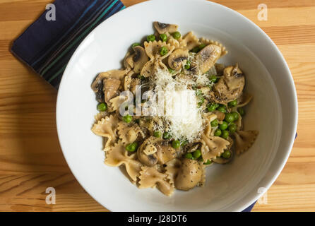 Nœud papillon, pâtes aux champignons, petits pois et fromage dans un bol blanc Banque D'Images