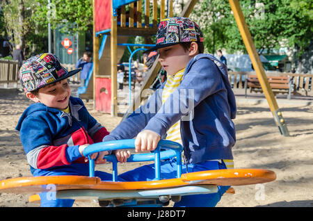 Jeunes Frères jouant sur une balançoire springer dans une aire de jeux pour enfants. Banque D'Images
