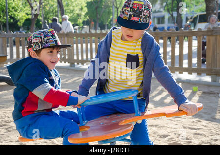 Jeunes Frères jouant sur une balançoire springer dans une aire de jeux pour enfants. Banque D'Images