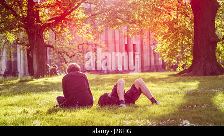 Jeune couple chill sur le pré dans la lumière du soleil du soir en face de Bruehl's terrasse ou le balcon de l'Europe. Printemps coloré sur la scène de l'Elbe à Dresde, Saxe, Allemagne, Europe Banque D'Images