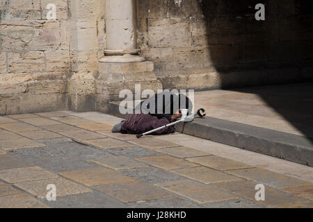 Une vieille femme mendiant sur les marches de la Cathédrale de Lisbonne, Portugal. Banque D'Images