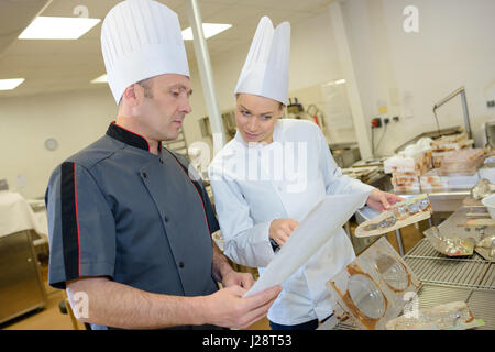 Homme et femme assistant chef preparing food in commercial Kitchen Banque D'Images