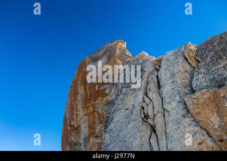 Détail de granite rock contre le ciel bleu avec des traces de fer rouge altérée et en surface avec des signes d'érosion Banque D'Images