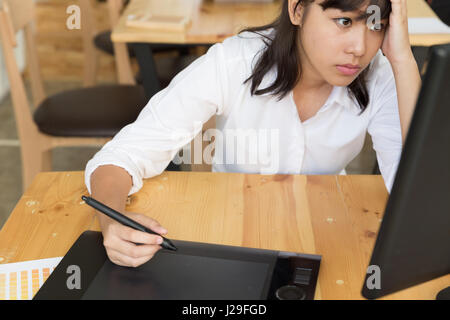 Freelance graphic designer sentiment épuisé, stressant et a des maux de tête, adhérents avec les mains au bureau avec tablette numérique couleur et cata Banque D'Images