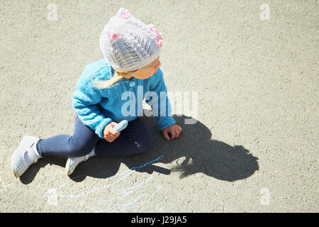 Petite fille attire la craie sur l'asphalte. enfant jouant à l'air libre à l'été Banque D'Images