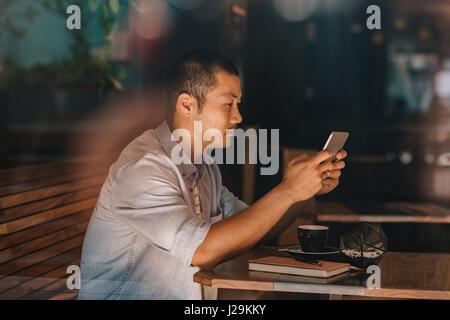 Young Asian man sitting in a cafe la navigation sur internet Banque D'Images