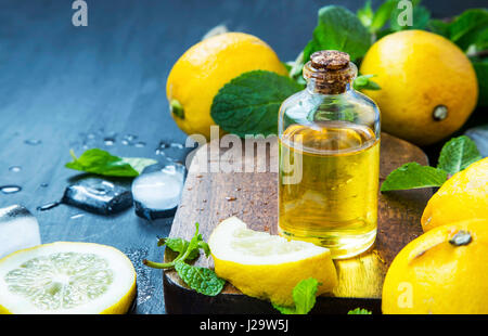 L'huile essentielle d'agrumes frais.l'huile de citron bouteille avec citrons fruits et feuilles de menthe Banque D'Images