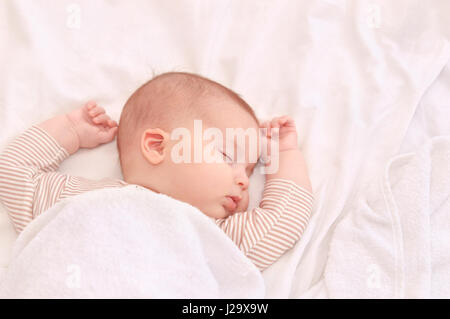 Bébé paisible sur un lit pendant le sommeil dans une salle lumineuse. Le Sommeil du nouveau-né. Les mains derrière la tête. Concept de la maternité heureuse Banque D'Images