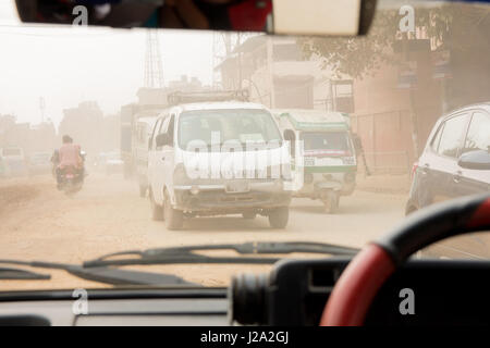 Traffic se précipite dans une atmosphère très poussiéreuse et polluée i street à Katmandou, au Népal. Tiré de l'intérieur d'une petite voiture de taxi. Banque D'Images