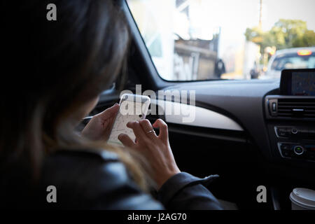 Au cours de l'épaule à l'aide de navigation téléphone dans une voiture Banque D'Images