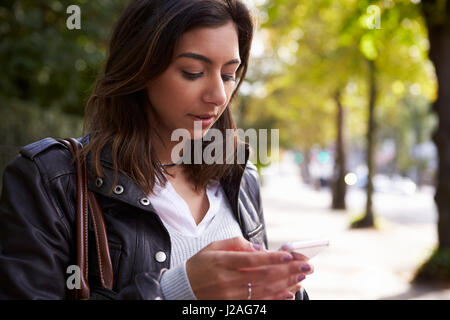 Young woman standing in street en utilisant un téléphone mobile, Close up Banque D'Images