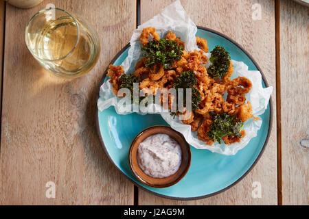 Calmars frits avec kale sur table avec verre, overhead view Banque D'Images