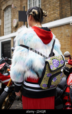 Londres - Février 2017 : young woman wearing fausse fourrure veste sur hoodie avec un sac à dos sur le dos, debout dans la rue lors de la London Fashion Week, vertical Banque D'Images