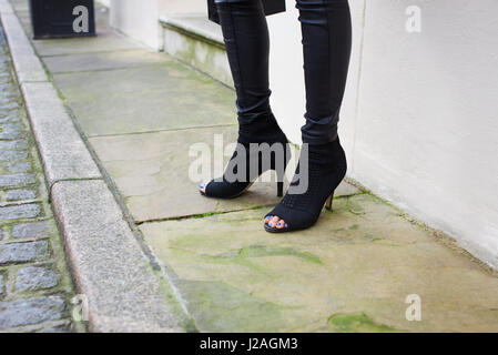 Londres - Février 2017 : woman standing in a street port ouvert toe Stiletto Heel boots en daim noir et un pantalon noir serré lors de la London Fashion Week, horizontal Banque D'Images