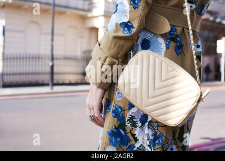 Londres - Février 2017 : Mid section of woman wearing white cross body sac à main Chanel et l'enduire de la décoration florale en rue pendant la Semaine de la mode de Londres Banque D'Images