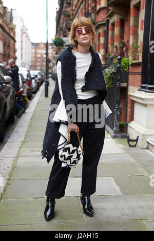 Londres - Février 2017 : Full length portrait of fashion blogger Xeni Kouveli standing in street holding sac Ferragamo, London Fashion Week, jour 4. Banque D'Images