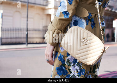 Londres - Février 2017 : Mid section of woman wearing white cross body sac à main Chanel et l'enduire de la décoration florale en rue pendant la Semaine de la mode de Londres Banque D'Images