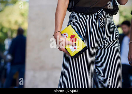 Femme portant un pantalon rayé holding purse, mid section Banque D'Images