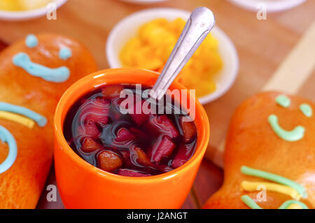 Configuration élégante de l'Amérique latine savoureux traditionnels pains de sucre coloré guagua, décorations, orange tasse avec colada morada jus de baies à côté de lui, le jour de la Dead concept Banque D'Images