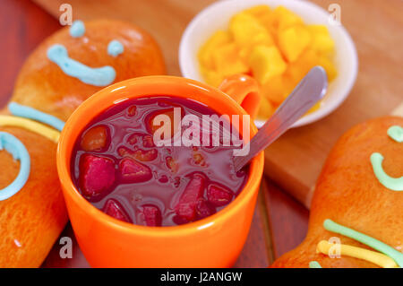 Configuration élégante de l'Amérique latine savoureux traditionnels pains de sucre coloré guagua, décorations, orange tasse avec colada morada jus de baies à côté de lui, le jour de la Dead concept Banque D'Images