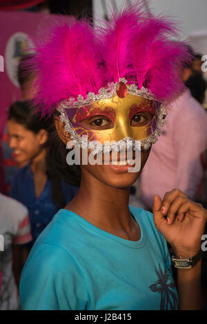 Une jeune femme s'occupe avec son masque pour voir le défilé du carnaval Banque D'Images