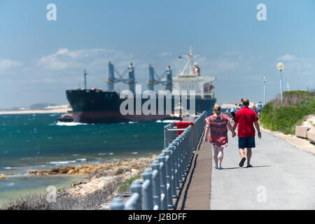 Un grand navire de charbon et de marcheurs de Nobbys Head passe au sortir de l'océan Pacifique et entre dans le port de Newcastle et de l'estuaire de la rivière Hunter, de l'Australie. Banque D'Images