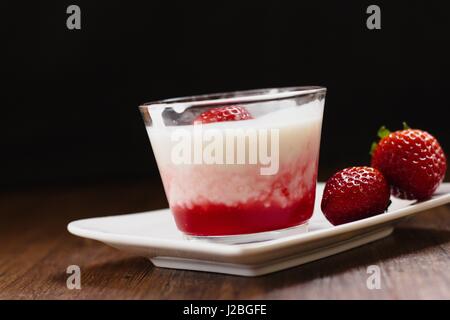Pouding au tapioca à saveur de fraise de coupe en verre sur la table en bois sombre et fond noir Banque D'Images