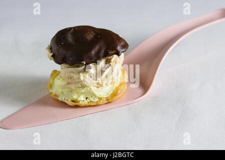 Chou à la crème fait maison avec haut enrobées de chocolat et deux sortes de crème servi sur nappe blanche Banque D'Images