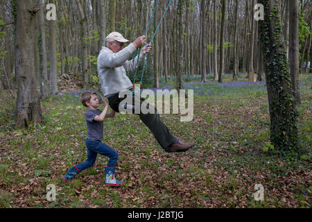 Un garçon de 7 ans pousse ses 75 ans, mon grand-père sur une balançoire en bois local, le 23 avril 2017, en Wrington, North Somerset, Angleterre. Banque D'Images