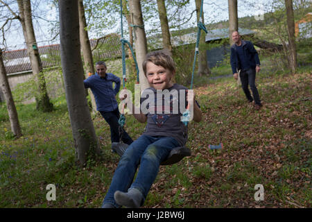 Un garçon de 7 ans joue sur une balançoire avec les membres de la famille dans les bois locaux, le 23 avril 2017, en Wrington, North Somerset, Angleterre. Banque D'Images