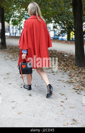 Femme en cape rouge marche avec sac à main dans la rue, vue arrière Banque D'Images