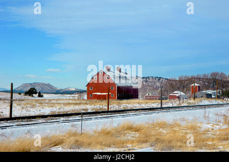 Pose de la neige autour des voies de chemin de fer et siège au toit de grange. Grange est un deux étages, rouge, bâtiment de bois. Banque D'Images