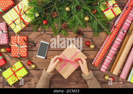 Les préparatifs de Noël avec des boîtes-cadeaux, du papier d'emballage et de l'arborescence sur table en bois Banque D'Images