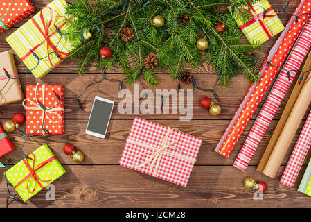 Les préparatifs de Noël avec des boîtes-cadeaux, du papier d'emballage et de l'arborescence sur table en bois Banque D'Images