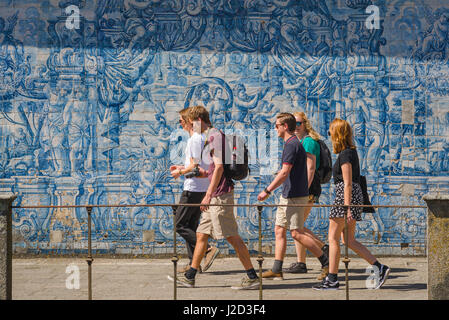 Jeunes Portugal, un groupe de jeunes marchent devant un mur dans la cathédrale se cloîtres décorées de tuiles azulejos bleues, Porto, Portugal, Banque D'Images