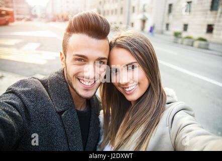 Happy young couple par selfies tél. mobile sur rue. Beau couple, l'amour et l'amusement selfies concept. Tonique, photo portrait. Banque D'Images