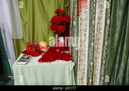 Still Life 'rouge sur un fond vert'.Red hat, plume, ventilateur et roses rouges sur fond de tissu et des rideaux dans des tons verts Banque D'Images