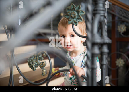 Petite fille de sourire et de regarder à travers une clôture métallique Banque D'Images