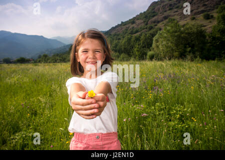 Young Girl standing in Field Holding Flower Banque D'Images