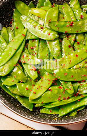 Les pois mange-tout avec des herbes et du citron en noir pan Banque D'Images