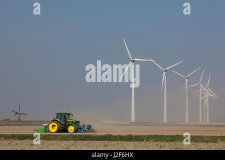 Le travail du tracteur de l'argile sèche dans le nord de Groningue, dans l'arrière-plan du moulin Goliath' et des éoliennes modernes' Banque D'Images