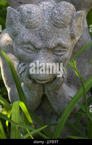 Close-up d'une sculpture de gargouille de granit gris dans un jardin à l'arrière à la fin du printemps Banque D'Images