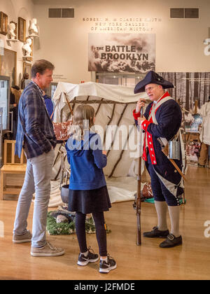 Porter l'uniforme d'un soldat continental dans la révolution américaine, un docent à la New-York Historical Society Museum de New York présente une exposition sur la bataille de 1776 à Brooklyn d'un père et sa fille. Remarque signe et tente dans l'arrière-plan. Banque D'Images